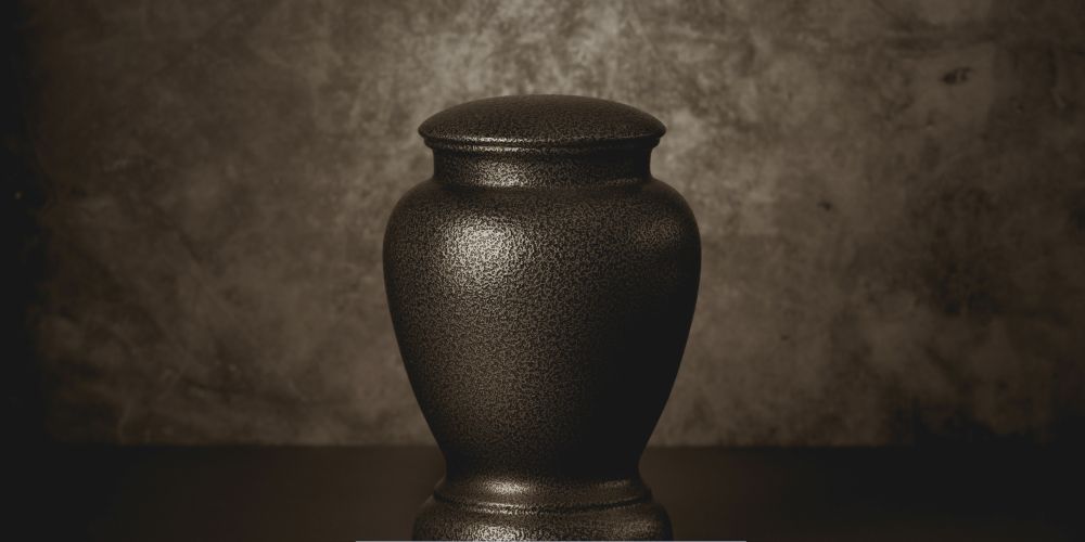 Elegant dark bronze cremation urn displayed against a textured background, representing Cremations in Milwaukee, WI.