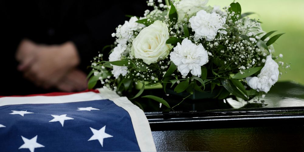 American flag draped over a casket with white floral arrangement at a funeral service in Funeral Home and Cremations in New Berlin, WI.