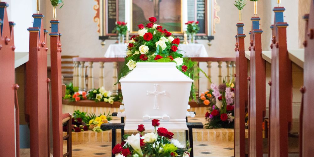 White casket with red and white rose arrangement at the altar during a service at Funeral Home and Cremations in Waukesha, WI.