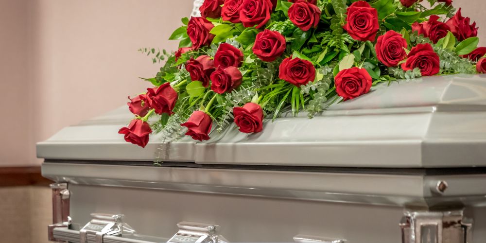 Silver casket adorned with red rose floral arrangement at a Funeral Home and Cremations in Milwaukee, WI.