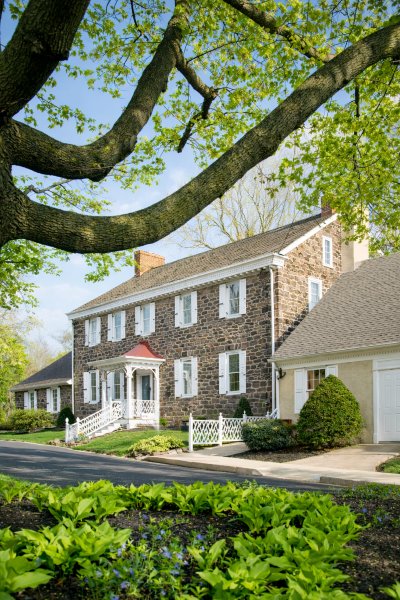 Historic stone building for Richboro, PA funeral home and cremations with landscaped gardens and white porch