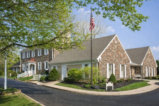 Stone building exterior for Southampton, PA funeral home and cremations with landscaped grounds and American flag