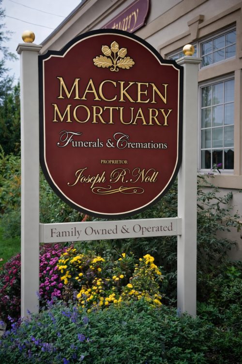 Macken Mortuary sign for Island Park, NY Funeral Home and Cremations with red and gold lettering