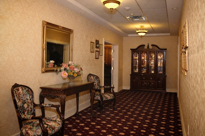 Traditional hallway interior at Long Beach, NY funeral home and cremations facility with chairs and floral table